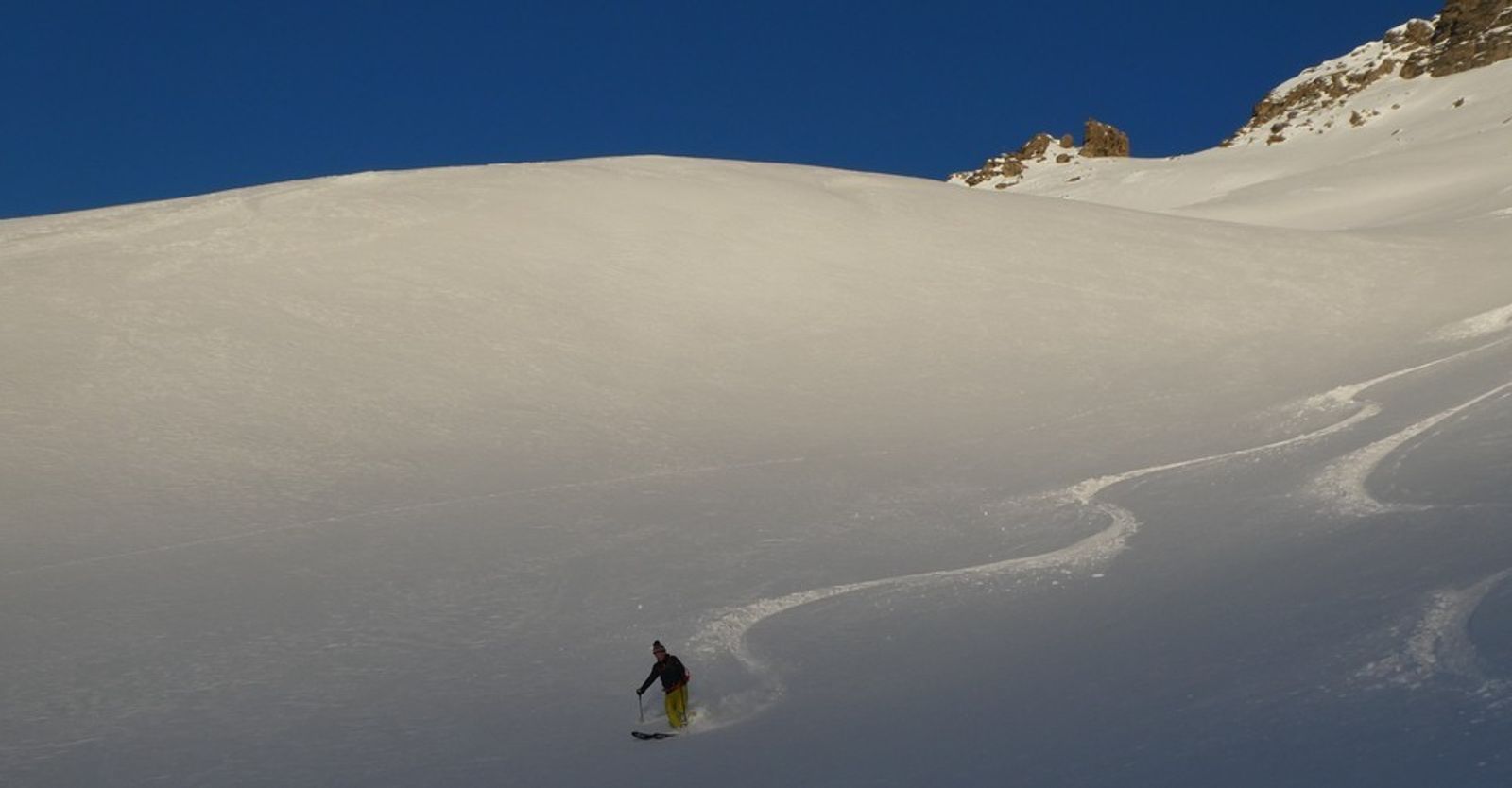Skieur traçant des virages dans une pente de poudreuse à Val Cenis.