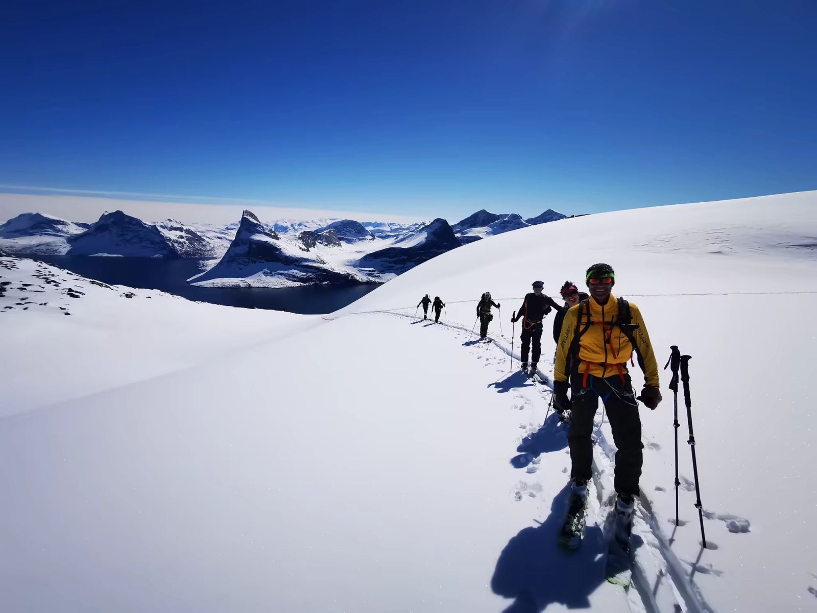 Groupe en montée à skis de randonnée sur un plateau enneigé du Groenland