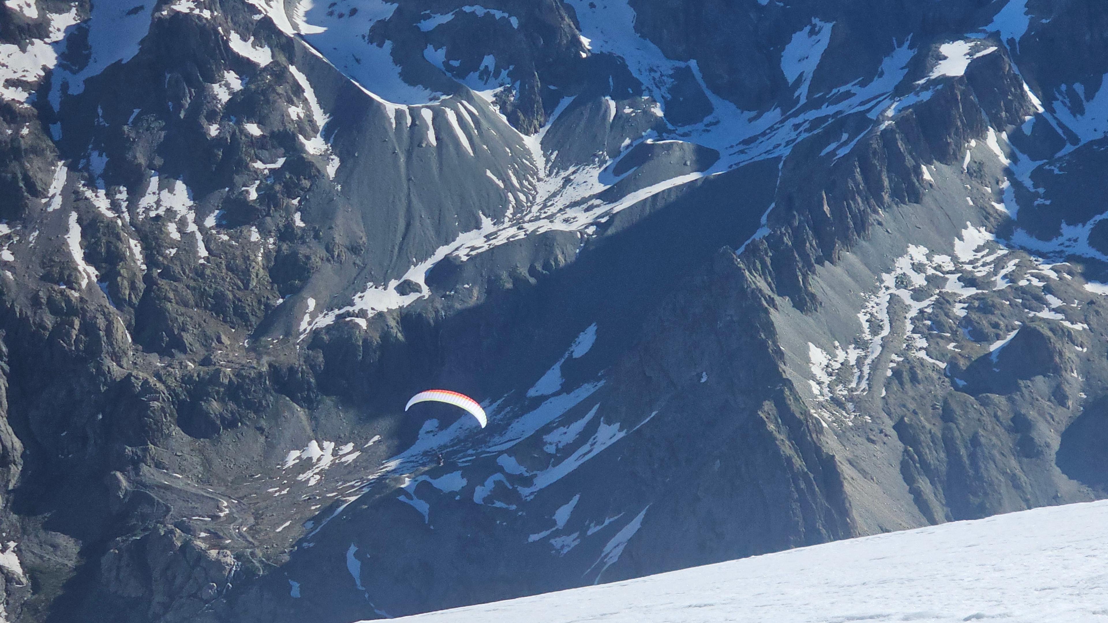 Parapente survolant les parois rocheuses du massif des Écrins