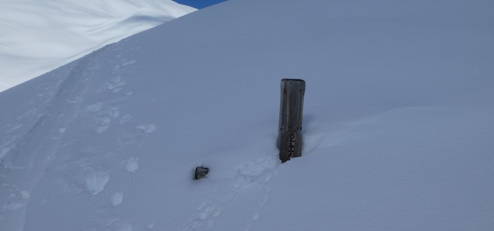 Vestige de la croix du Chastellet dépassant d’une pente enneigée près de Pelvoux.
