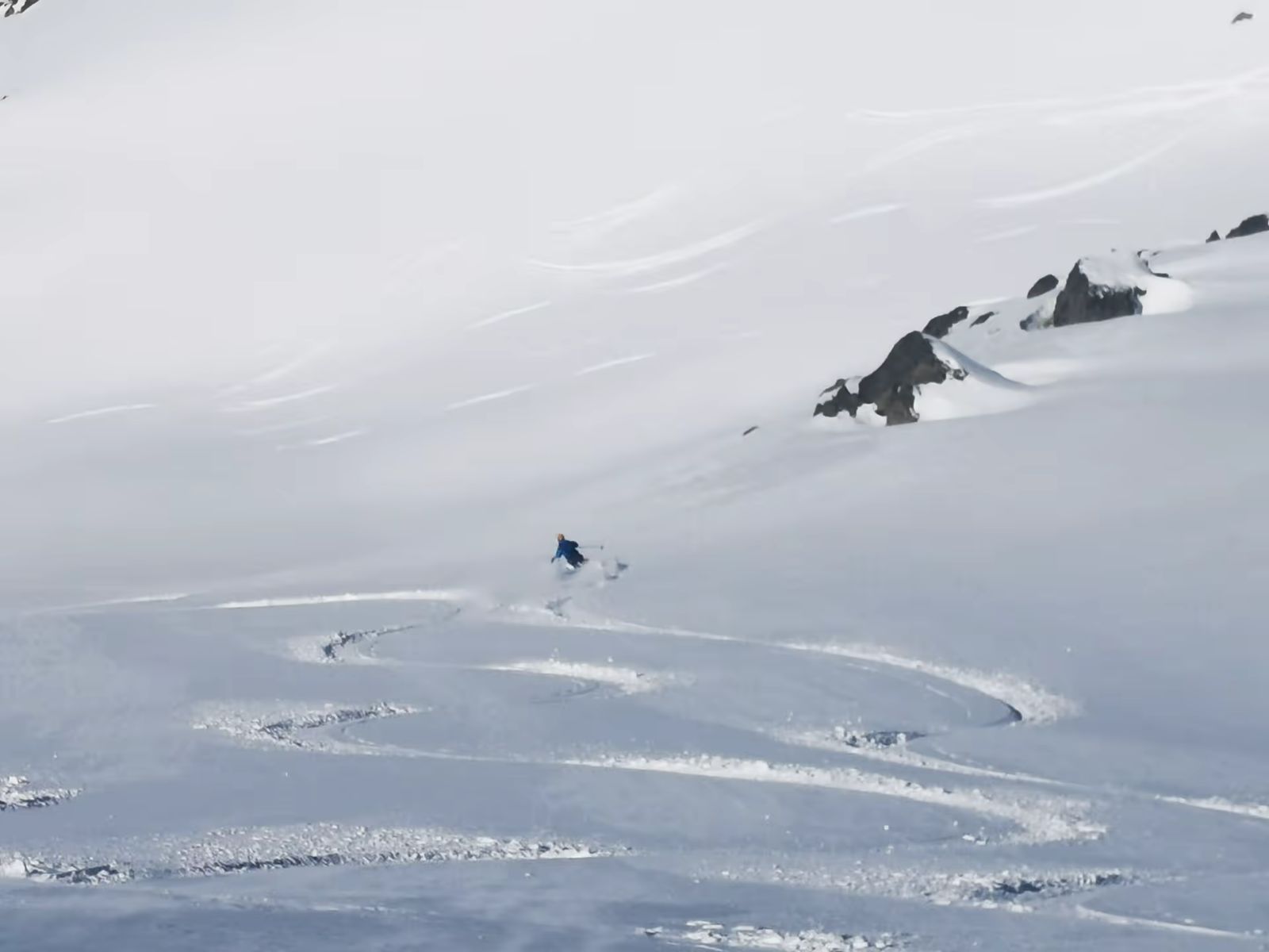Skieur traçant de grandes courbes dans la poudreuse du massif des Cerces