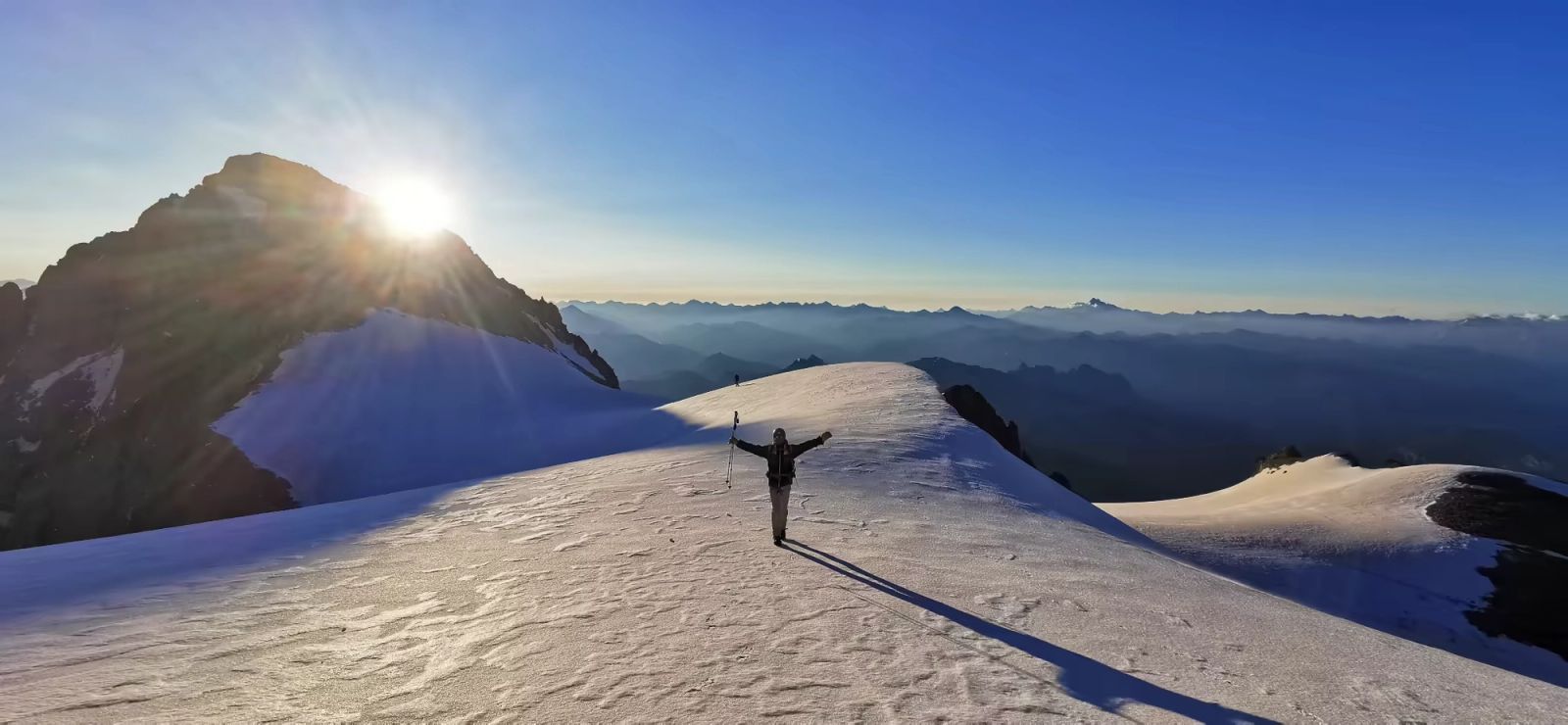 Alpiniste progressant sur l'arête enneigée du Pelvoux dans la lumière du matin au dessus de la Pente centrale