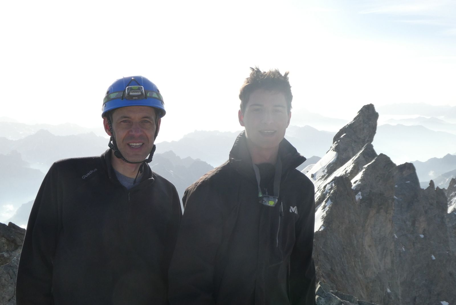 Pierre et Paul posent côte à côte au sommet du Grand Pic de la Meije, avec les arêtes en arrière-plan.