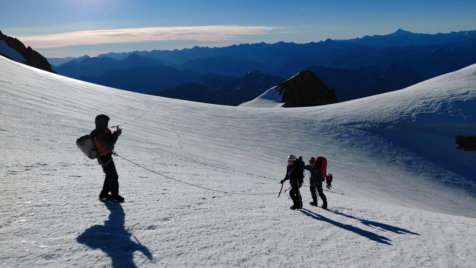 Guide photographe filmant une cordée sur le glacier des Violettes au levé du jour