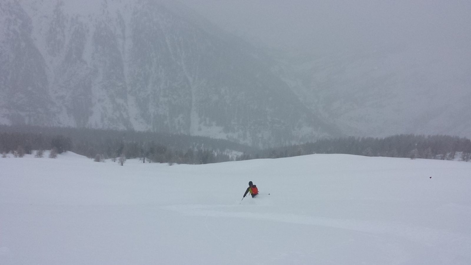 Skieur en veste rouge descendant une pente de neige fraîche à Maloqueste.