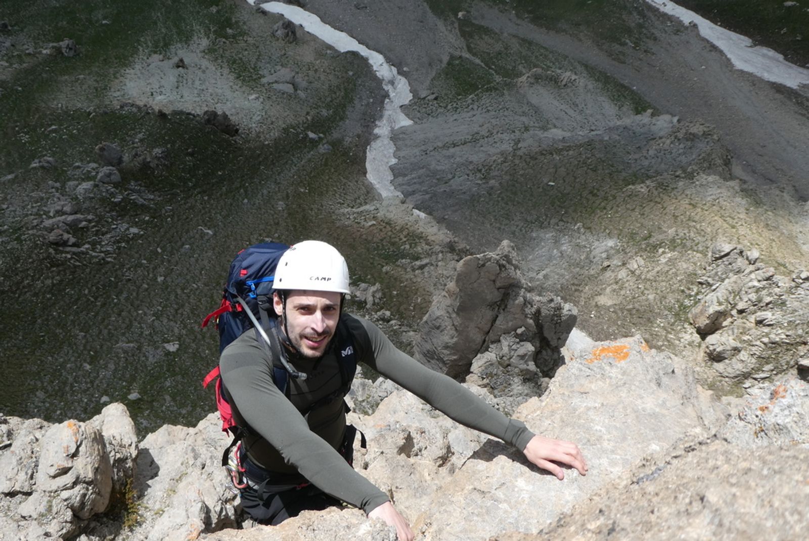 Tom, casque blanc, grimpe un passage aérien de l’arête sud de la Tête de Gaulent au-dessus de la vallée.