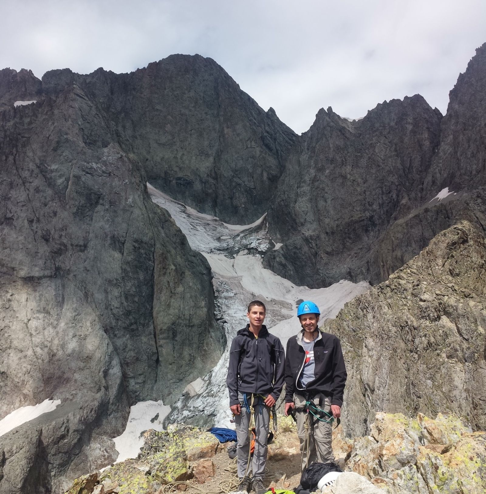 Pierre et Paul posant sur les rochers devant les parois et les névés du massif des Bans