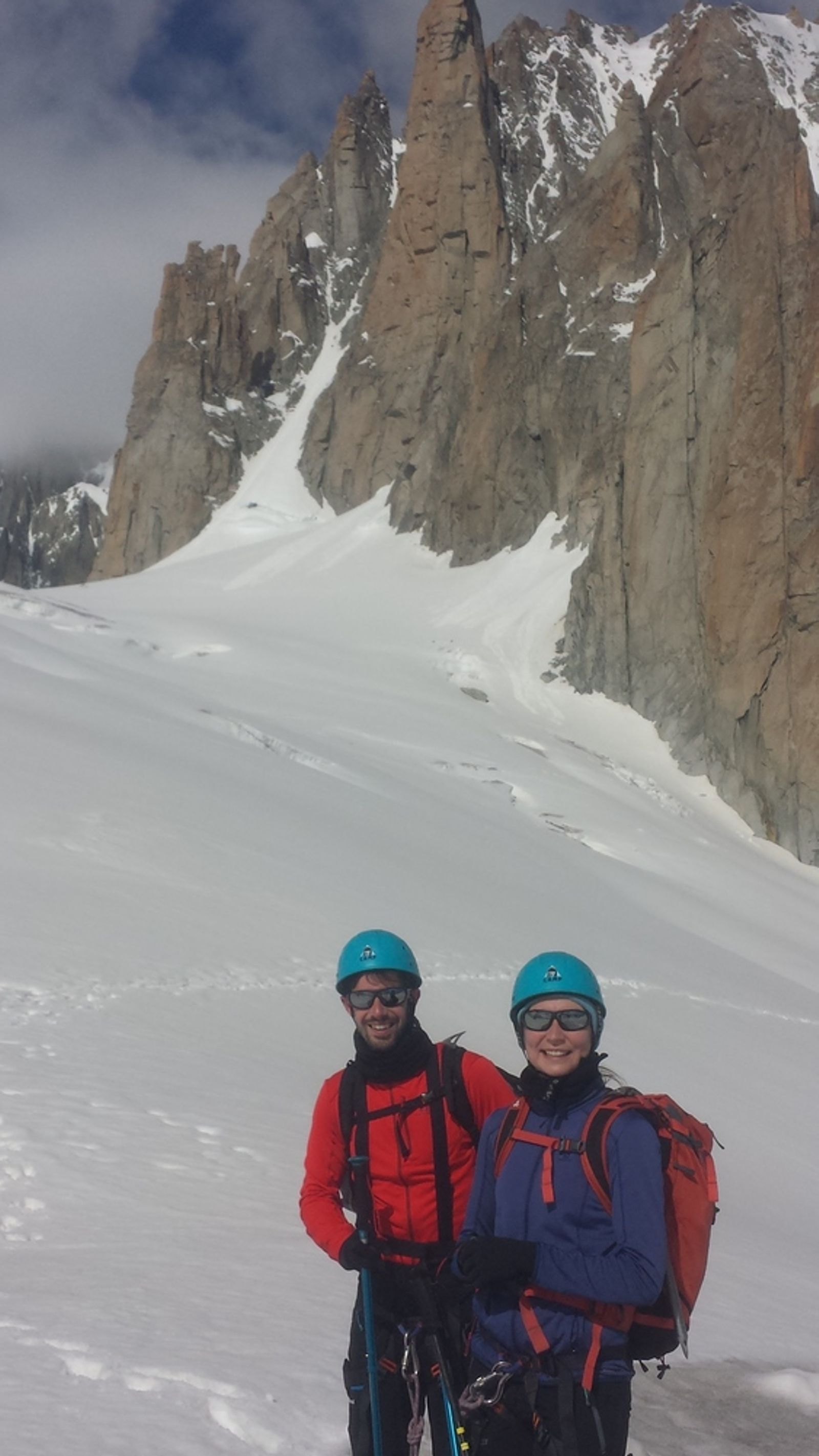 Julien et Erika posent sur le glacier, sous les hautes parois rocheuses du Grand Capucin.