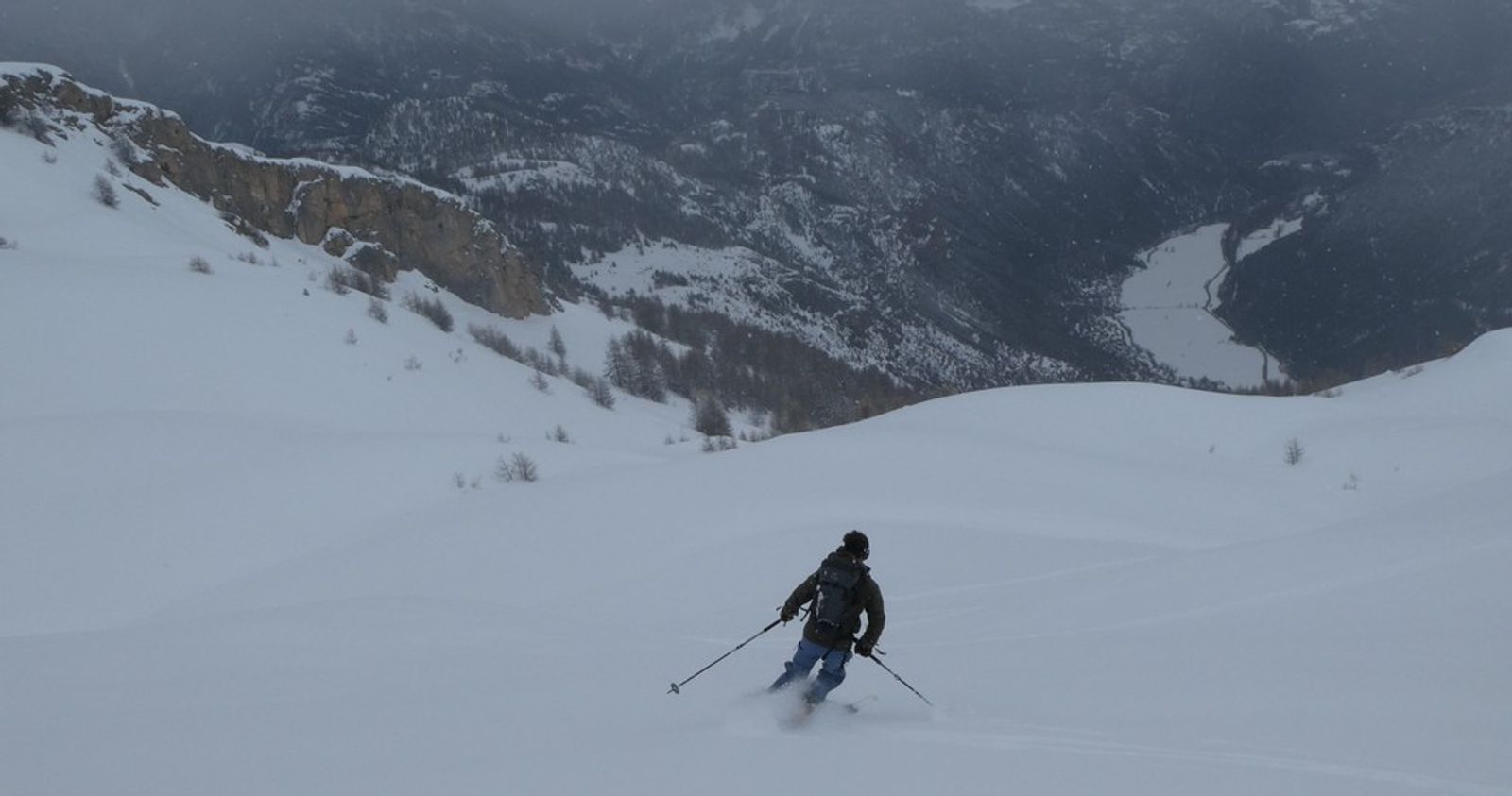 Skieur à la descente en ski de randonnée avec vue plongeante sur la vallée de Freissinières