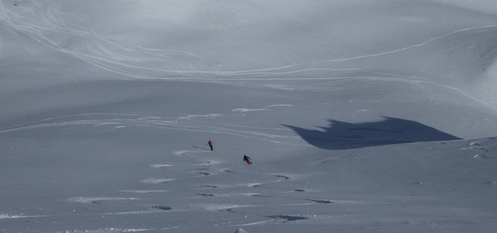 Antoine et Josh descendent une grande combe poudreuse près du col de la Masse.