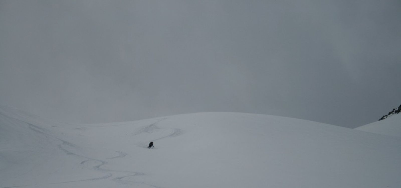 A skier descending a vast snow-covered valley below the Cime du Grand Vallon.