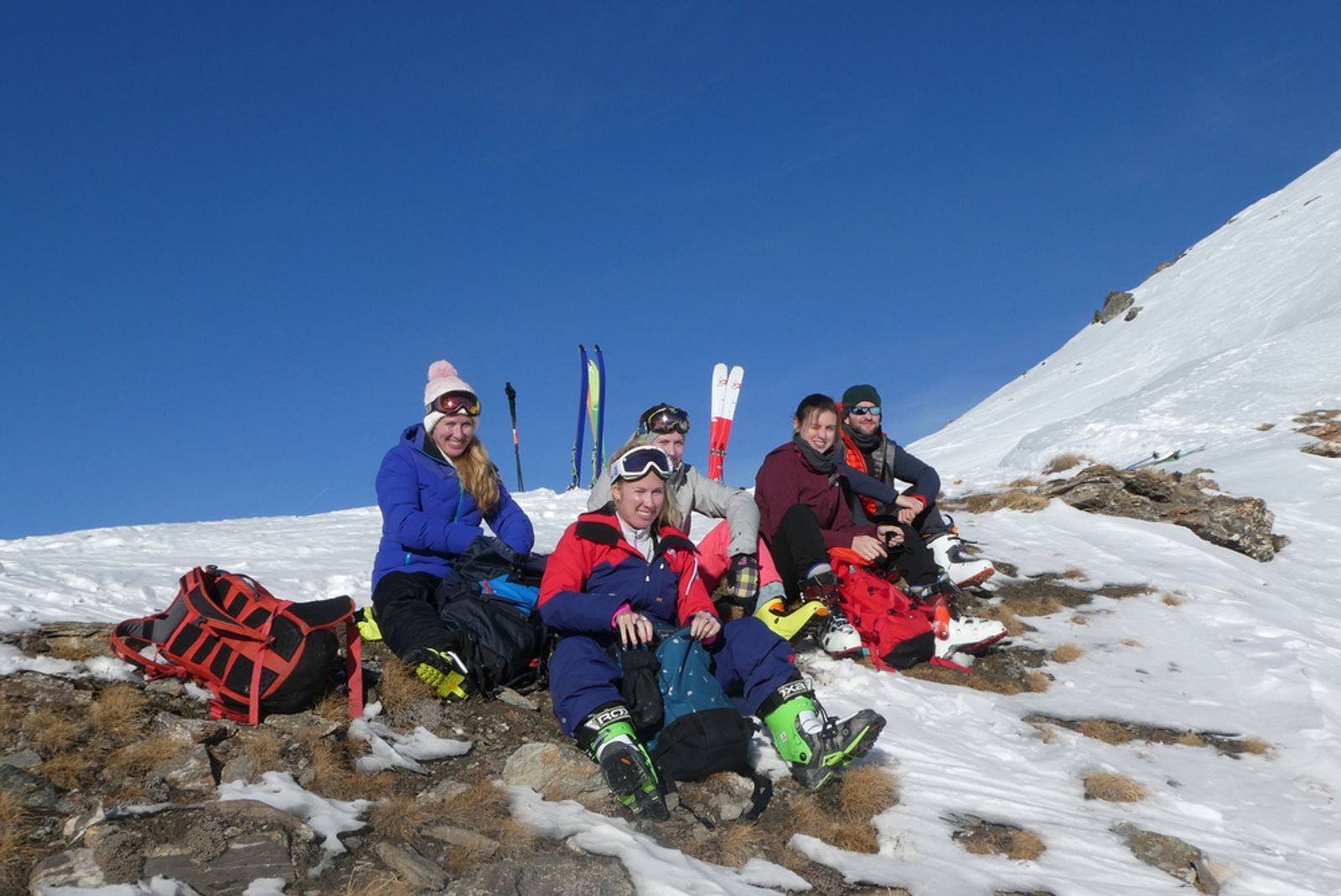 A group of skiers having a picnic on the grass at the summit of Cornivier