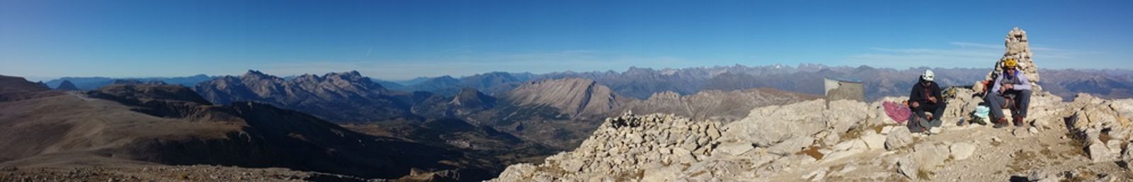 Panorama depuis le plateau de Bure, avec des grimpeurs assis près d’un cairn