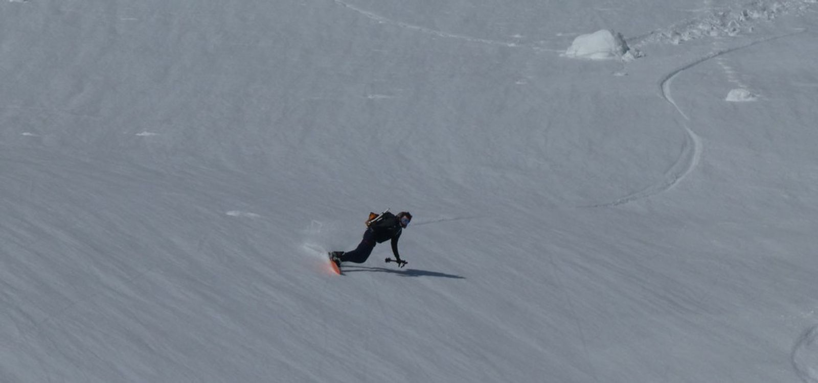 Splitboard en grande courbes, bâtons dans une main
