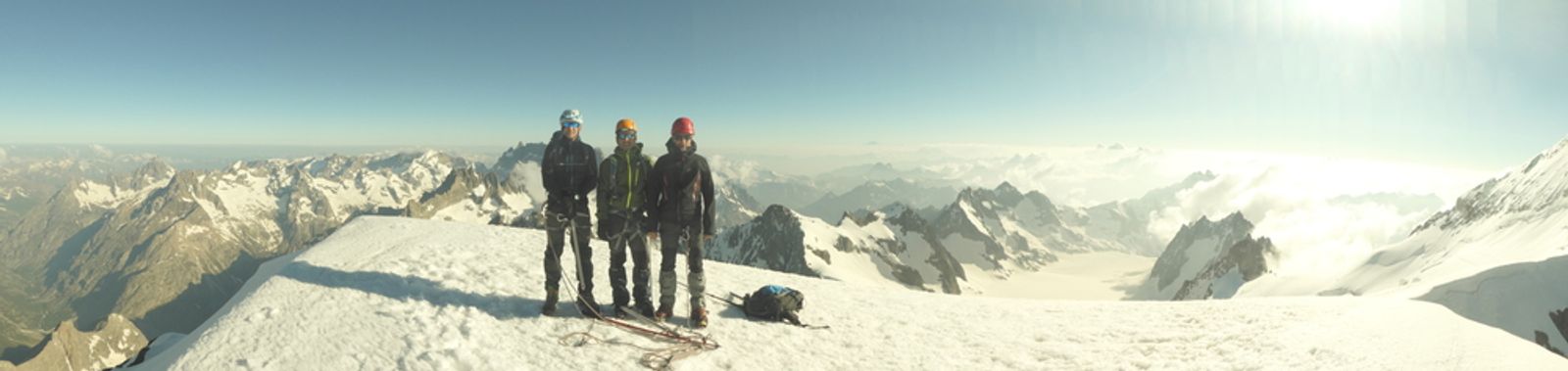 Vue panoramique du groupe au sommet du Dôme des Écrins, entouré de montagnes enneigées.