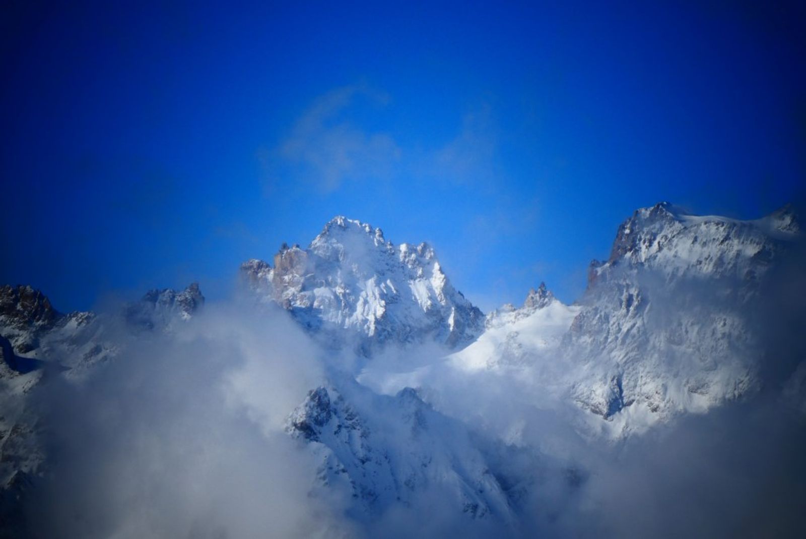 Sommets enneigés des Écrins émergeant des nuages, vus depuis la crête de la Lauze.