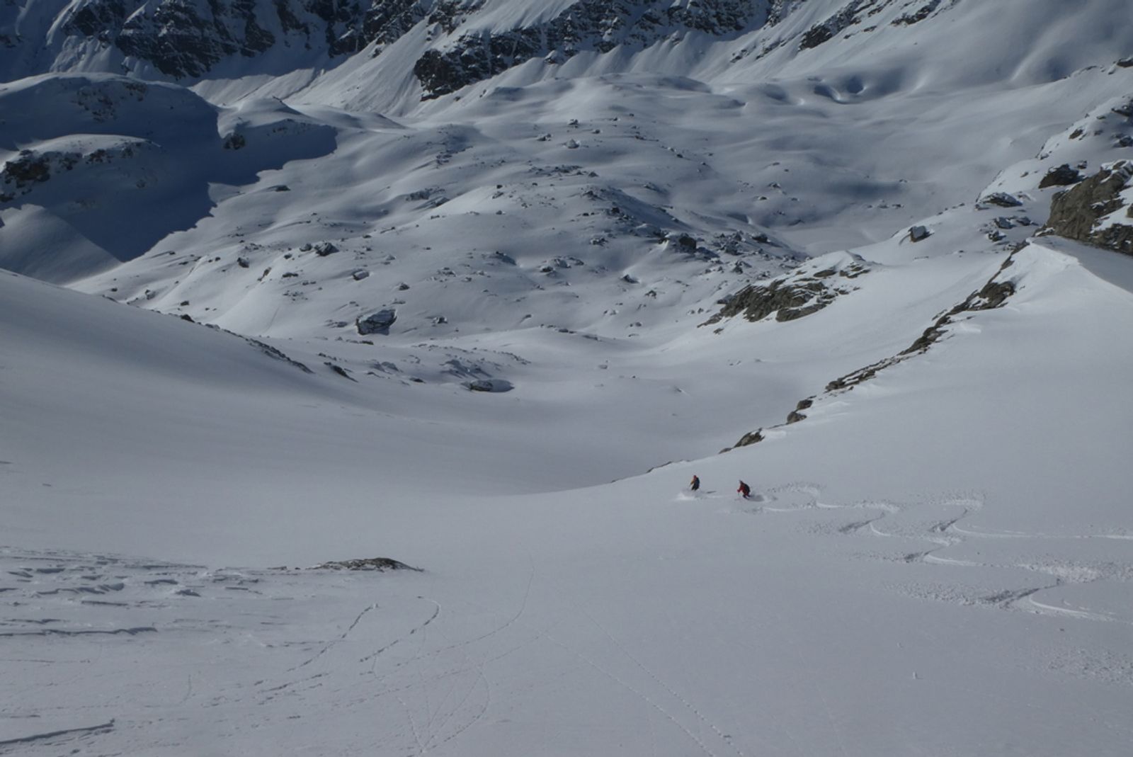 Skieurs descendant les grandes pentes enneigées de la combe du Ravin Noir.