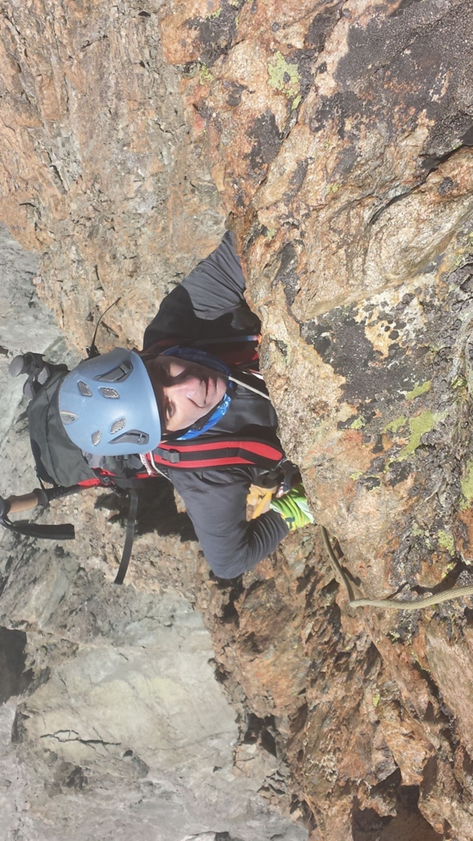 Ivan en casque bleu grimpant dans le rocher orangé du pilier sud de Barre Noire
