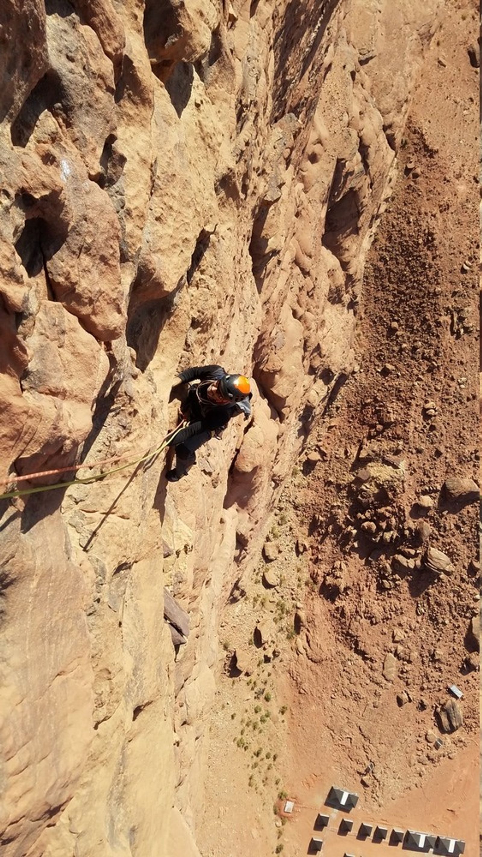 Grimpeur dans Atayek avec vue plongeante sur un campement bédouin