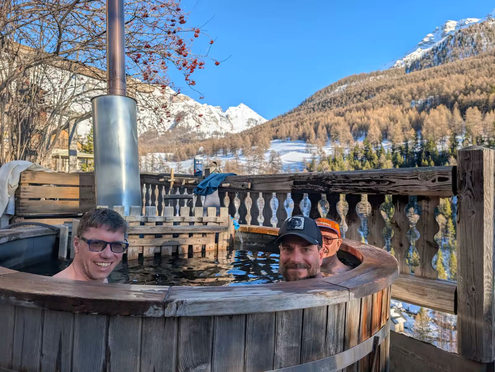 3 skieurs heureux dans un bain chaud à Fouillouse avec un beau paysage enneigé derrière