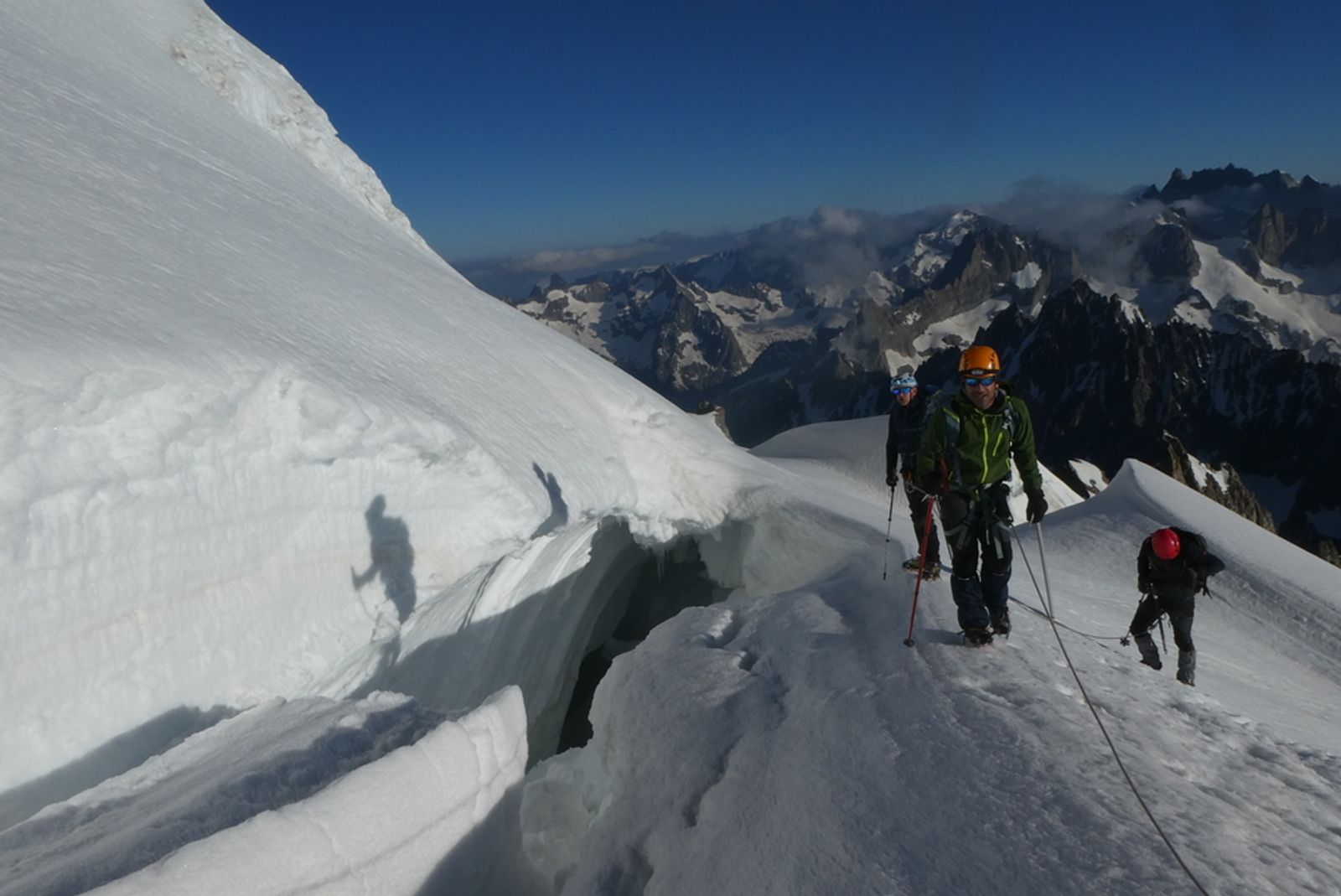 La cordée progresse près d’une crevasse entre les parois de neige du Dôme des Écrins.