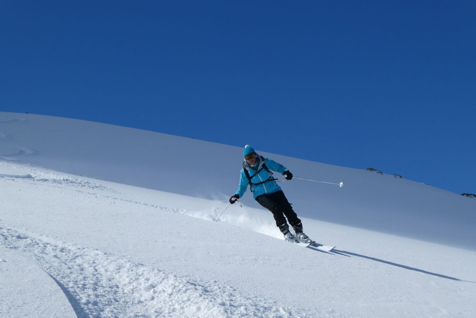 Skieuse qui fait de beaux virages d'initiation à la poudreuse à Pelvoux