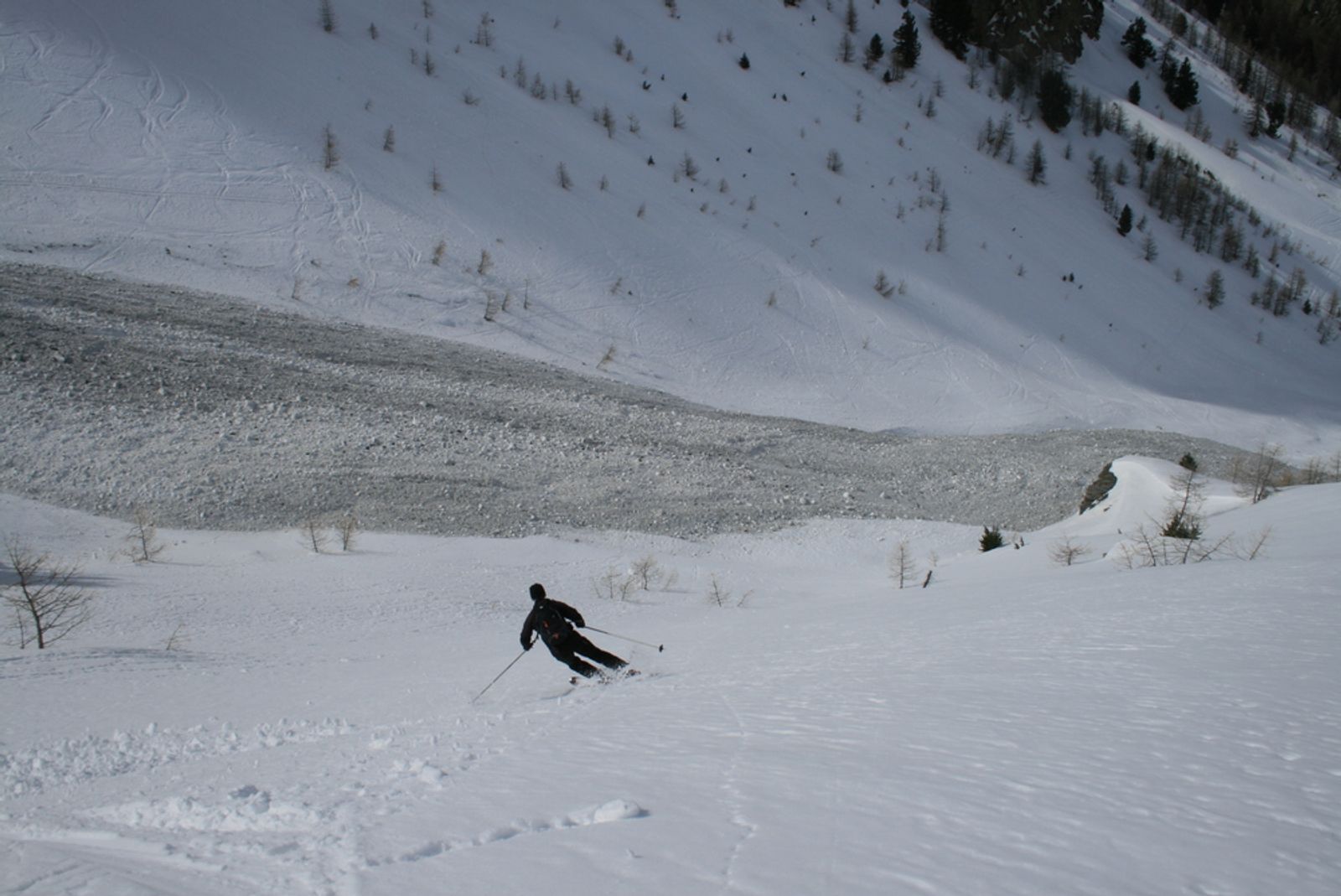 Skieur qui ski devant une coulée de neige humide