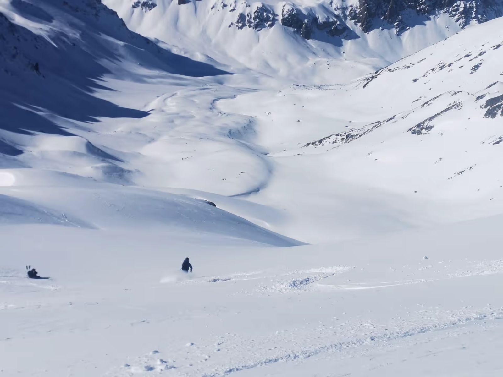 Skieurs descendant un vaste vallon enneigé lors d’un raid dans les Cerces