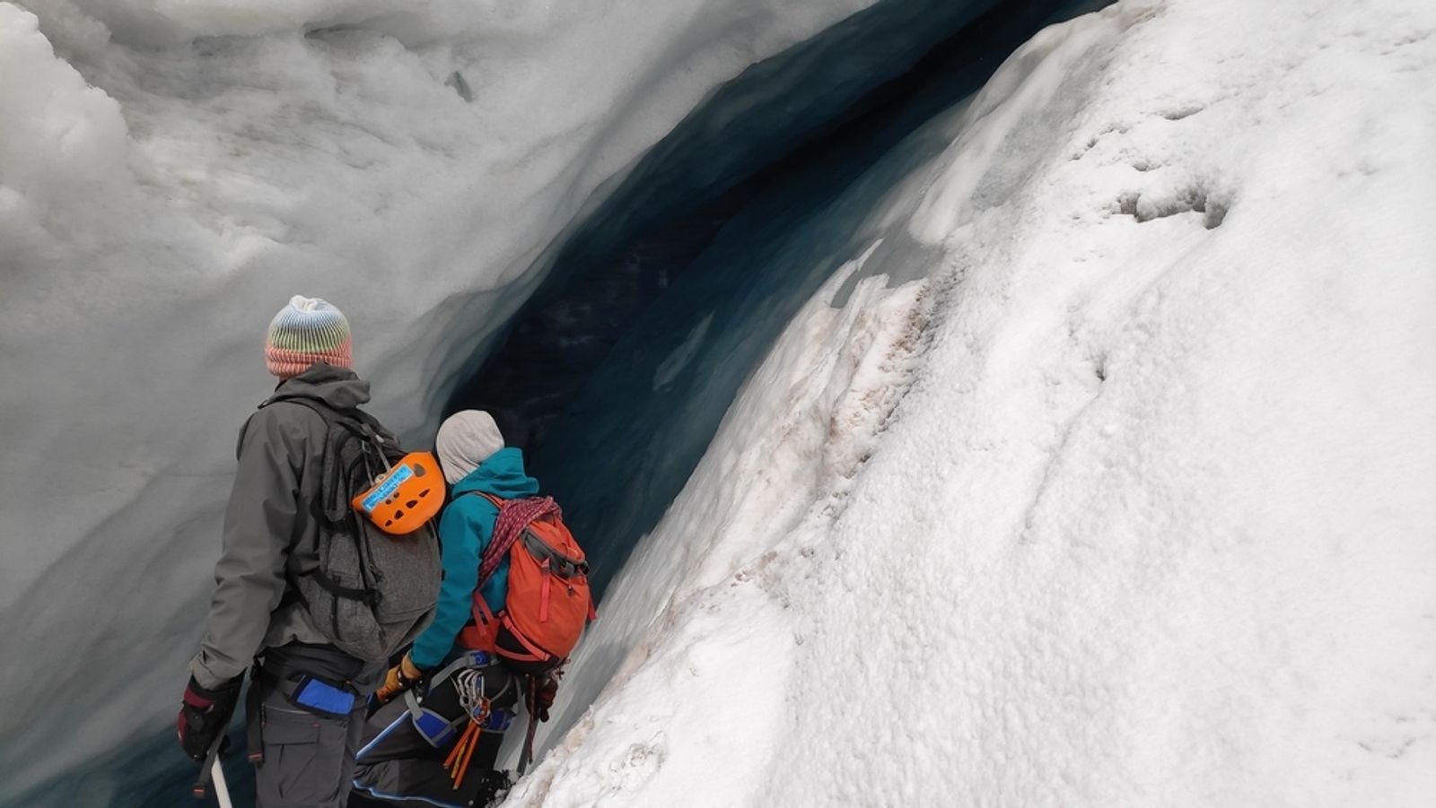 Participants encordés au bord d’une crevasse à la glace bleutée sur le Glacier Blanc.
