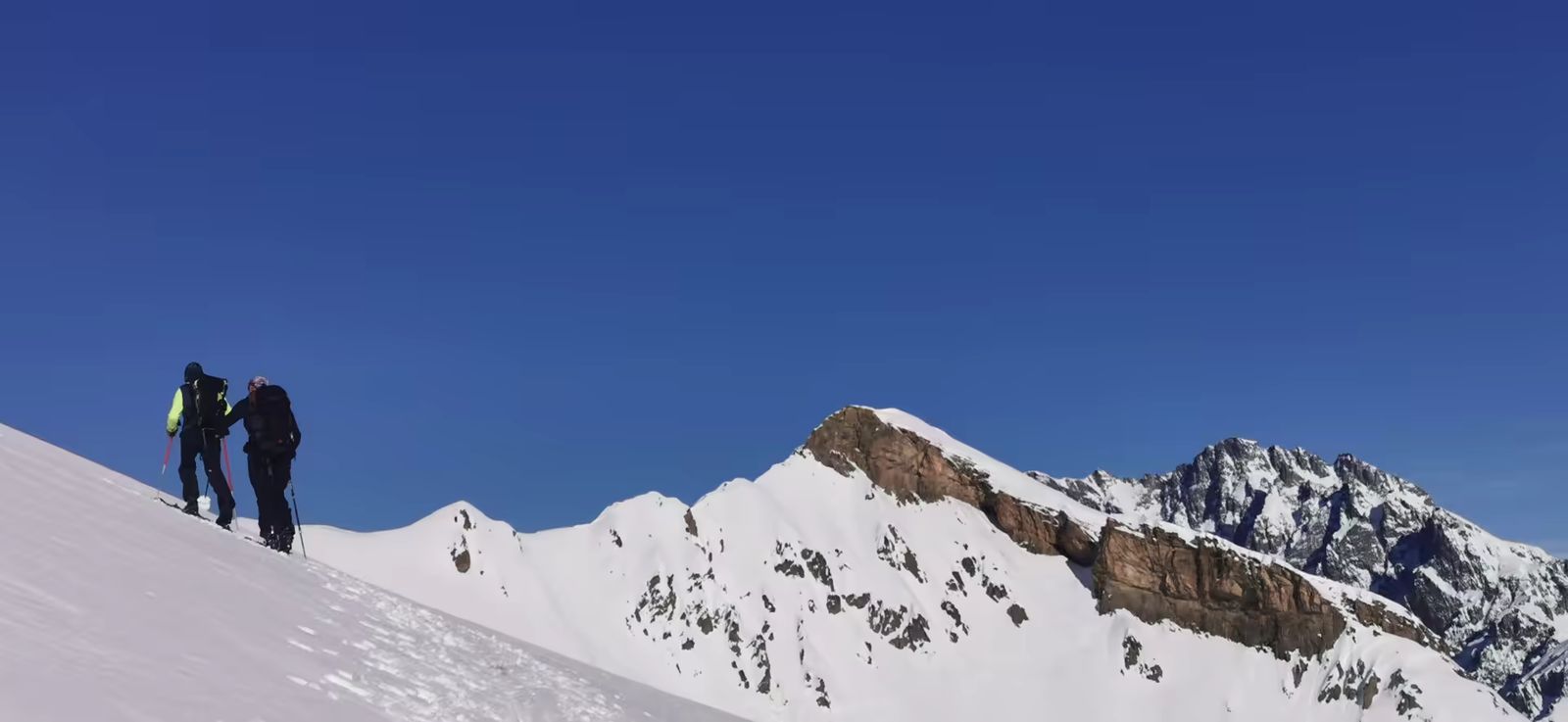 Deux skieurs montant dans un paysage magnifique avec la Rouya en fond
