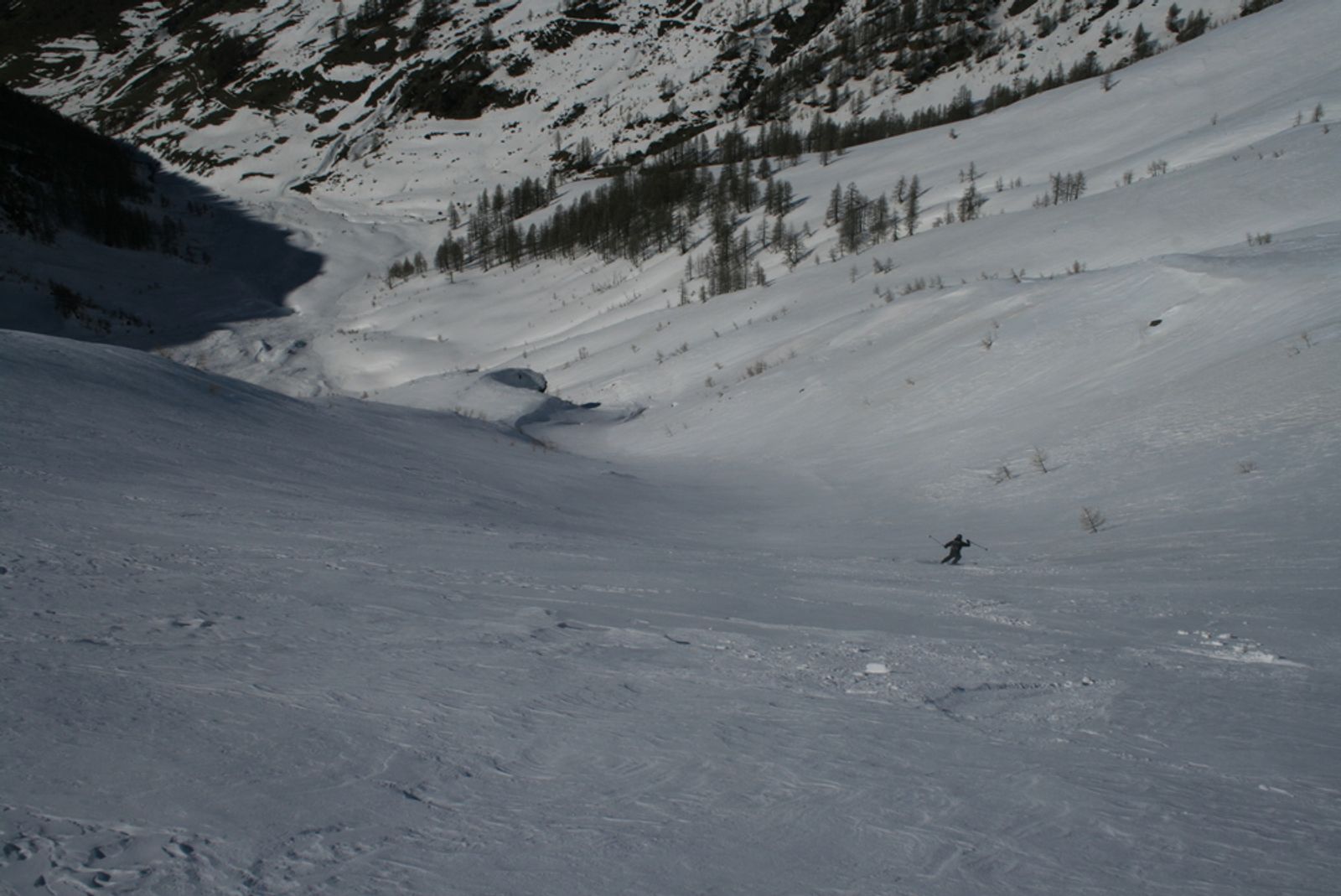 Skieur descendant une large pente vers les mélèzes sous le Maït d’Amunt.