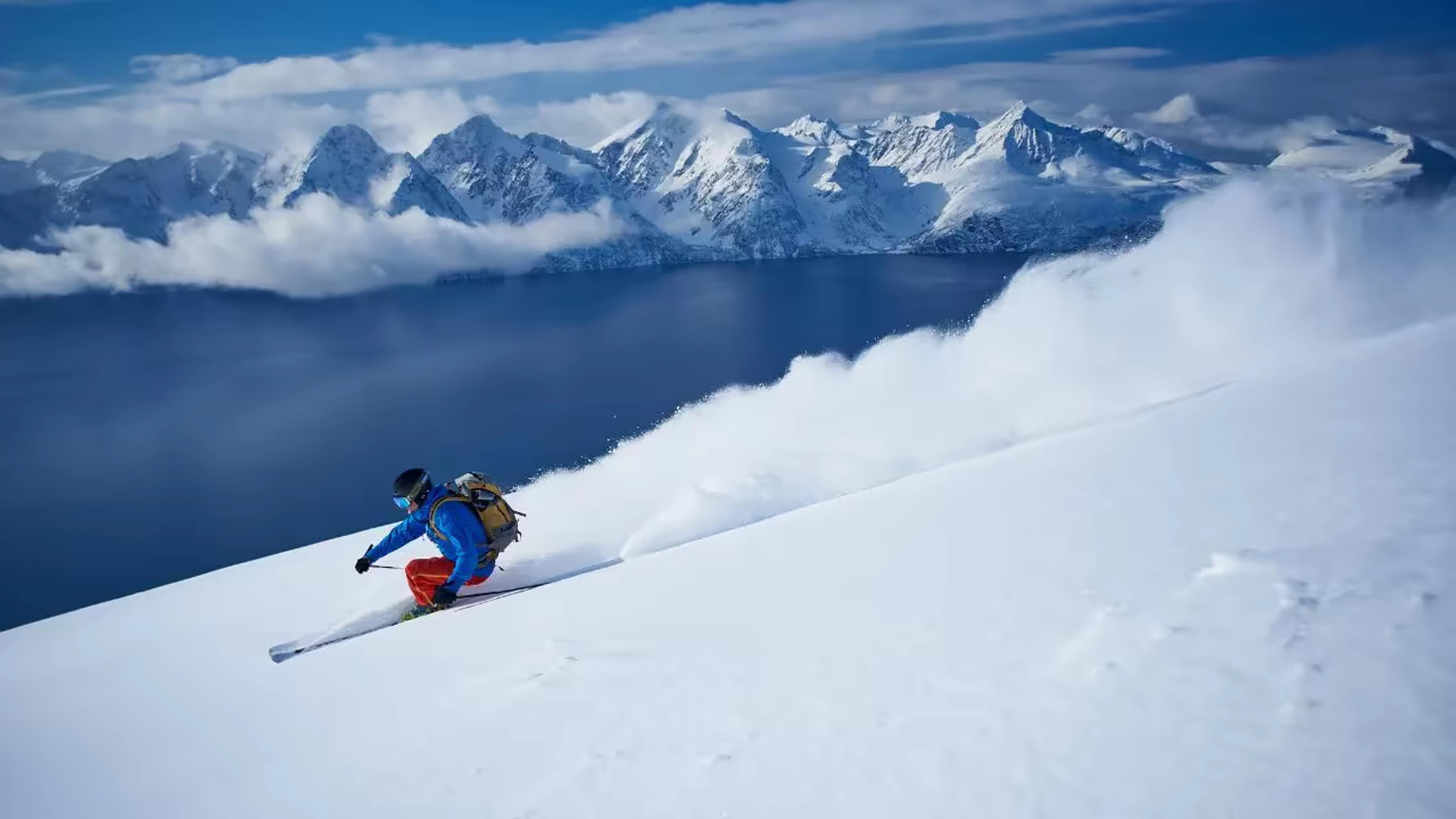 Skieur en poudreuse sur une pente dominant un fjord norvégien