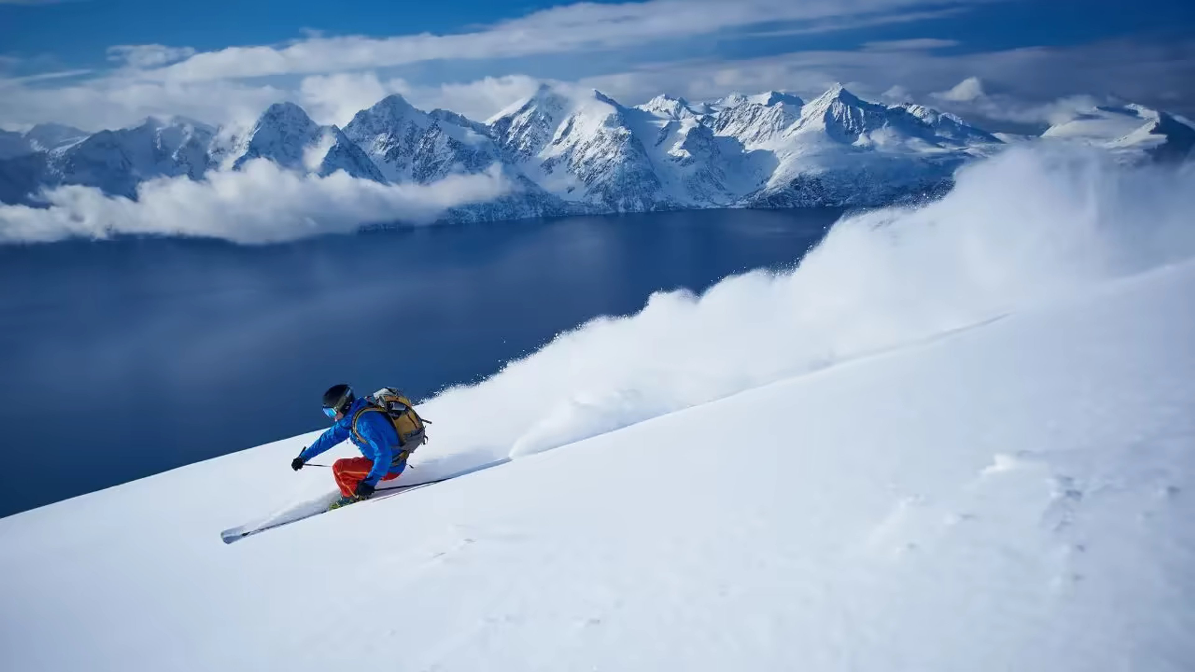 Skieur en poudreuse sur une pente dominant un fjord norvégien