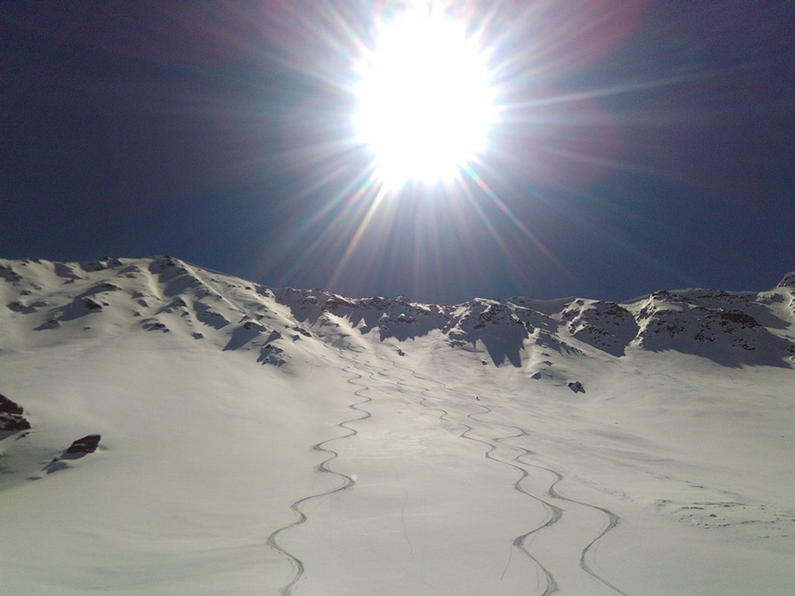 Skieur en virage dans une combe de poudreuse sous le Rocher Blanc