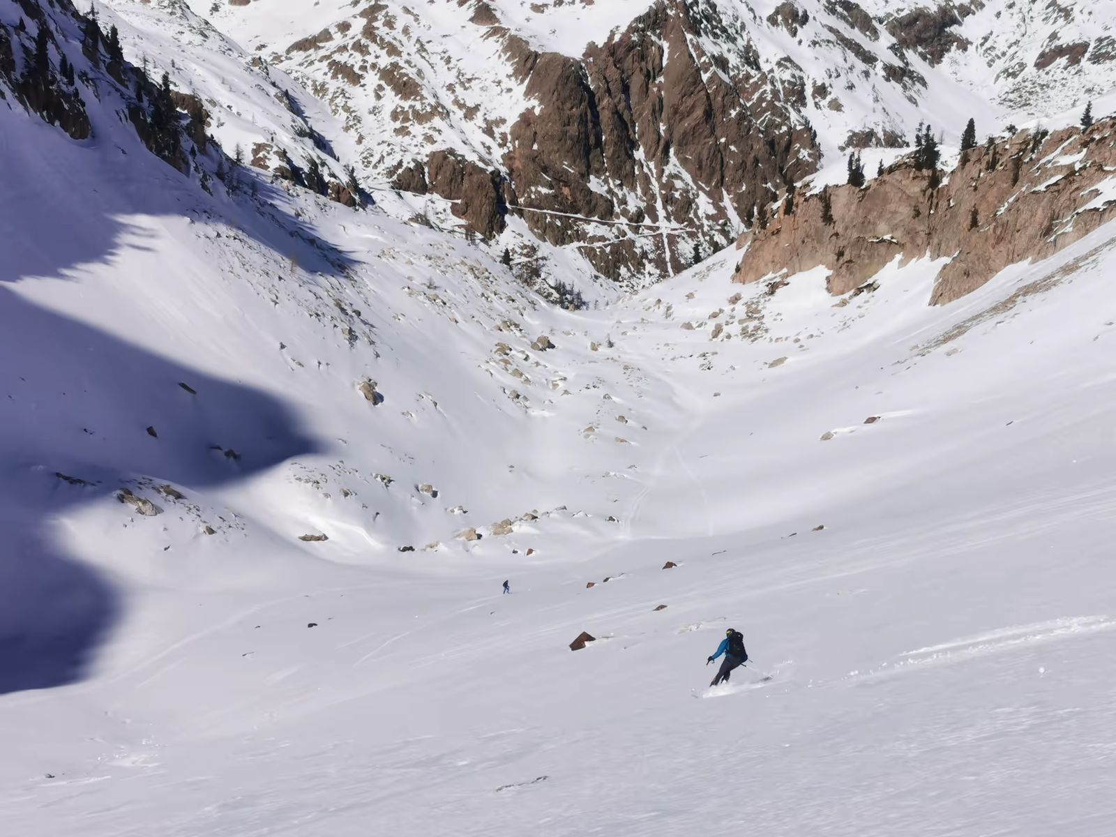 Skieur descendant un vaste vallon poudreux dans le Mercantour