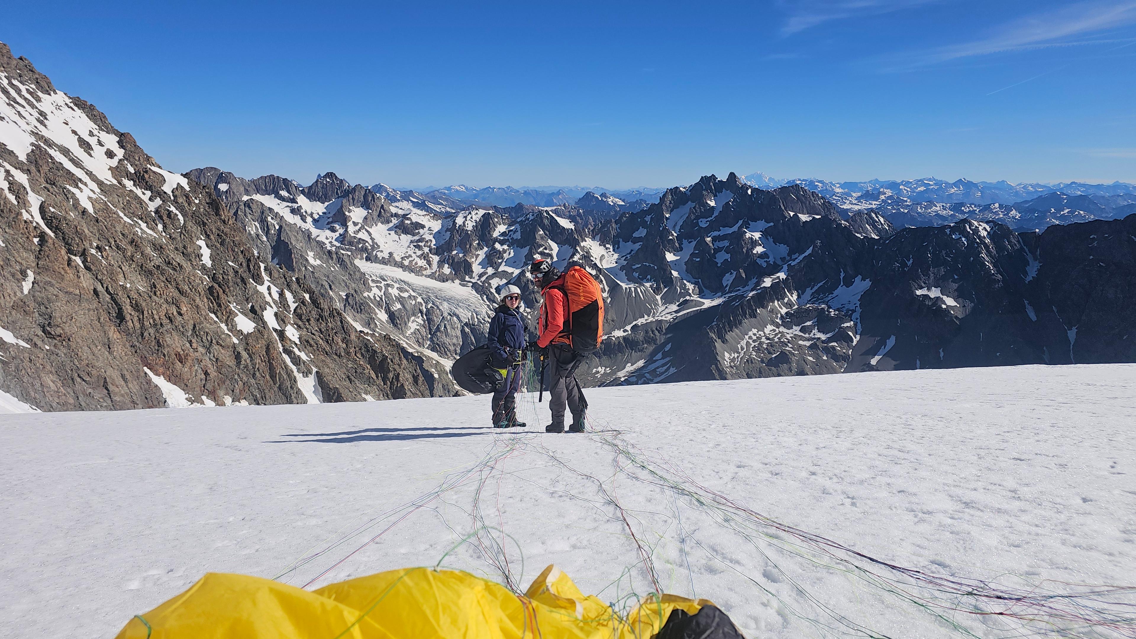 Préparation d'une voile de parapente jaune sur le glacier du Pelvoux