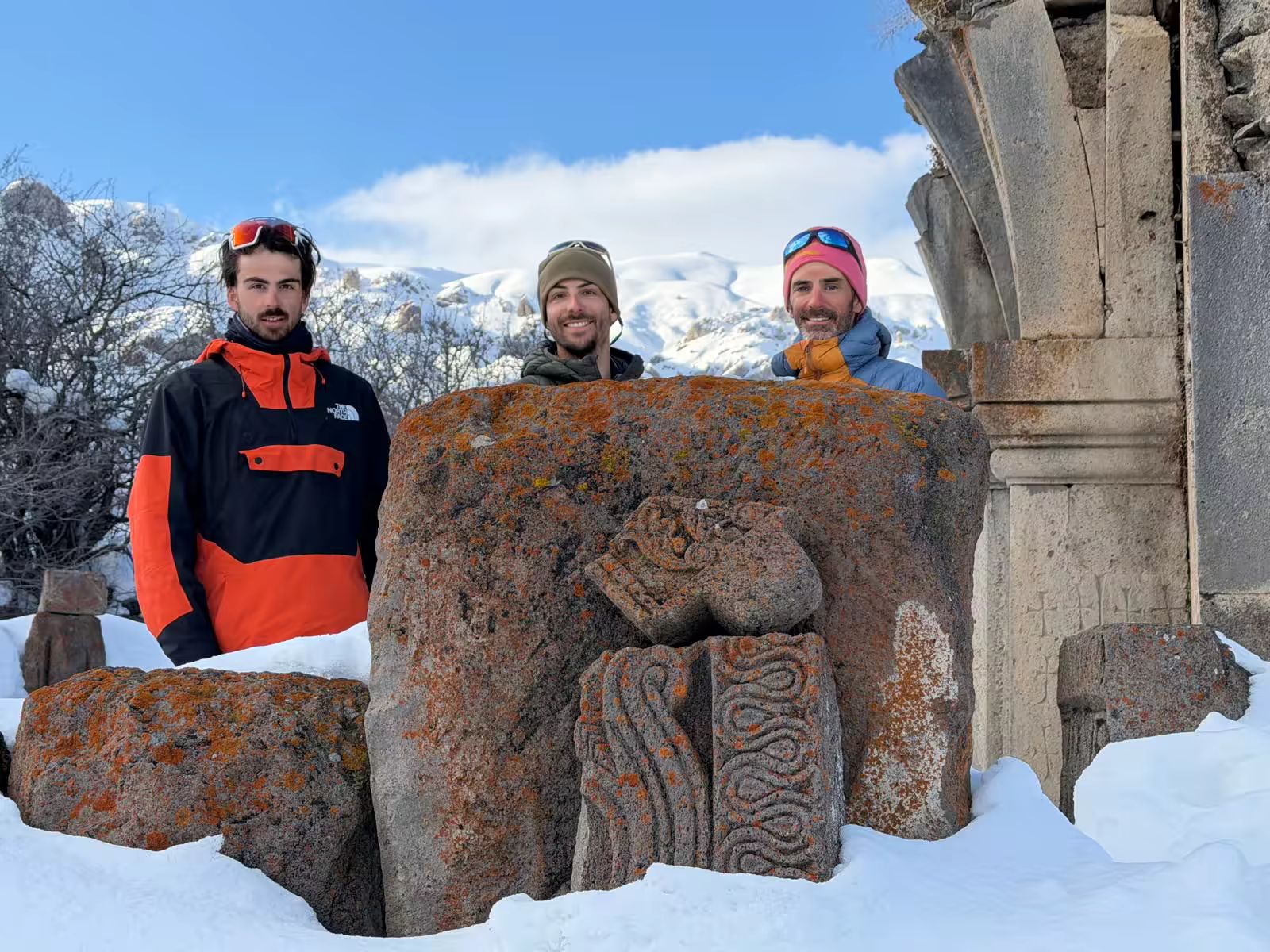 Trois voyageurs cachés derrière un khatchkar arménien