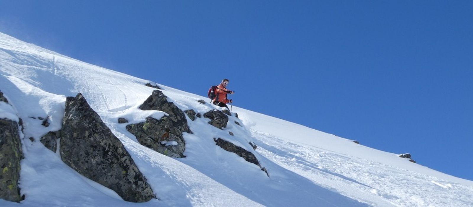 Lolo dans les rochers avant un grand champ de poudreuse