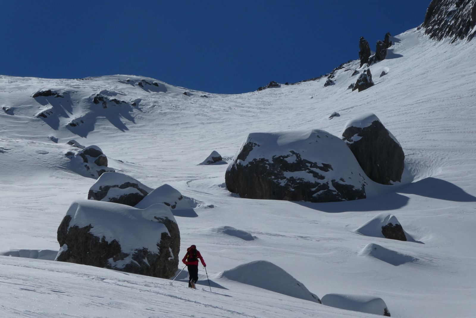 Slalom entre des gros blocs pleins de poudreuse en montant vers le col sans nom depuis Fouillouse