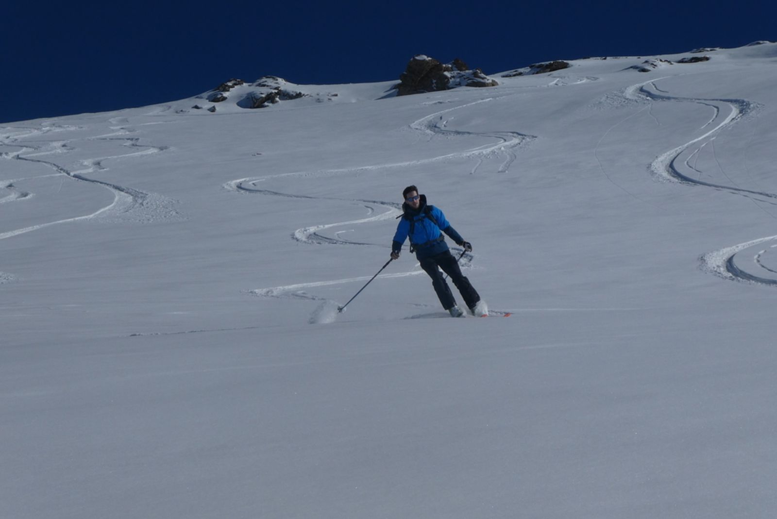 Un skieur à la veste bleu dans les champs de poudreuse de Saint Véran
