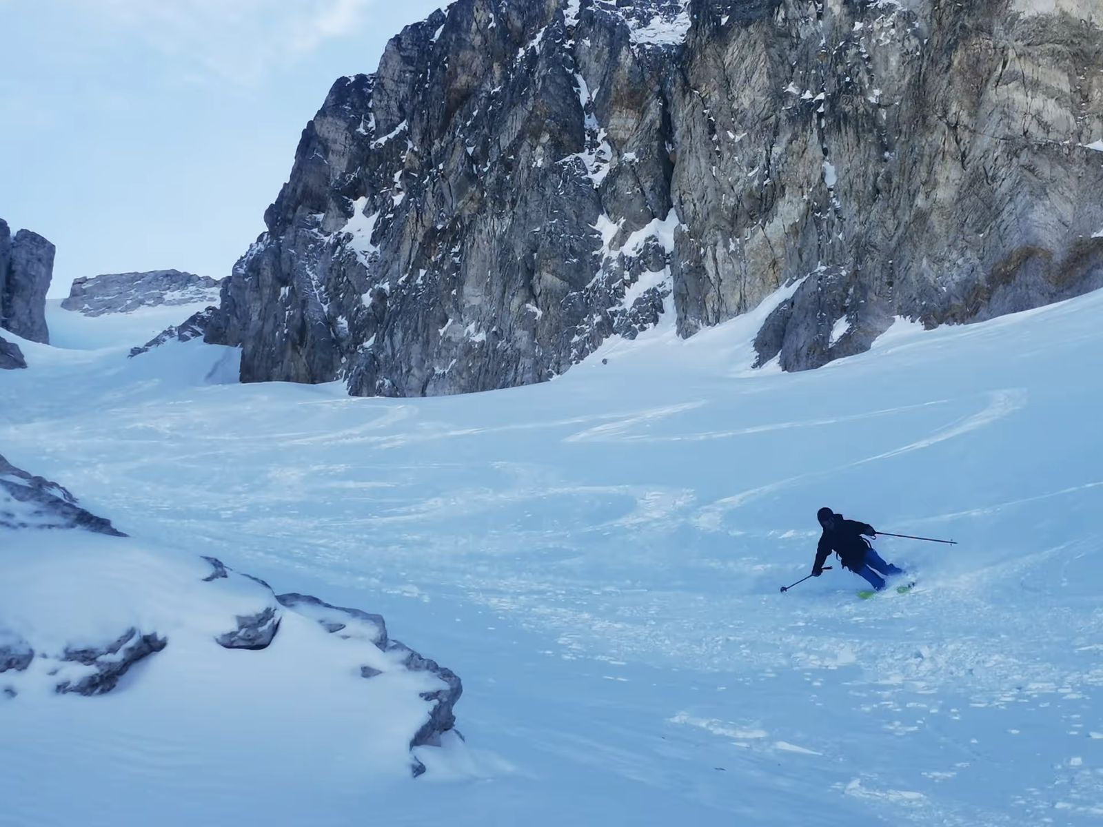 Skieur en descente dans un couloir bordé de rochers dans les Cerces