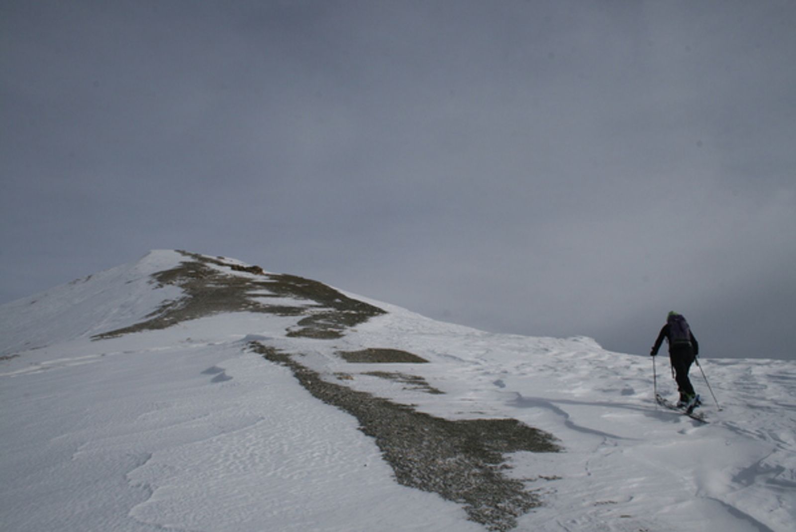 Skieur sur la crête du Girardin, où le vent a dégagé des bandes de roche.