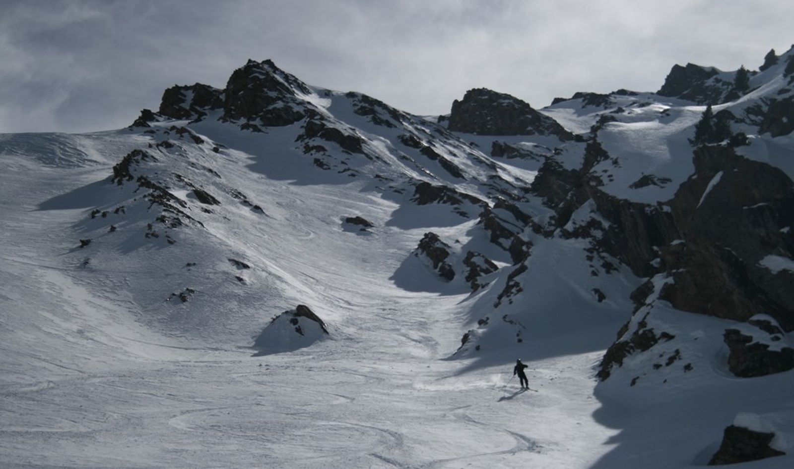 Skieur dans la poudre tassée au pied des couloirs de la Pointe des Marcelettes, dans le Queyras.