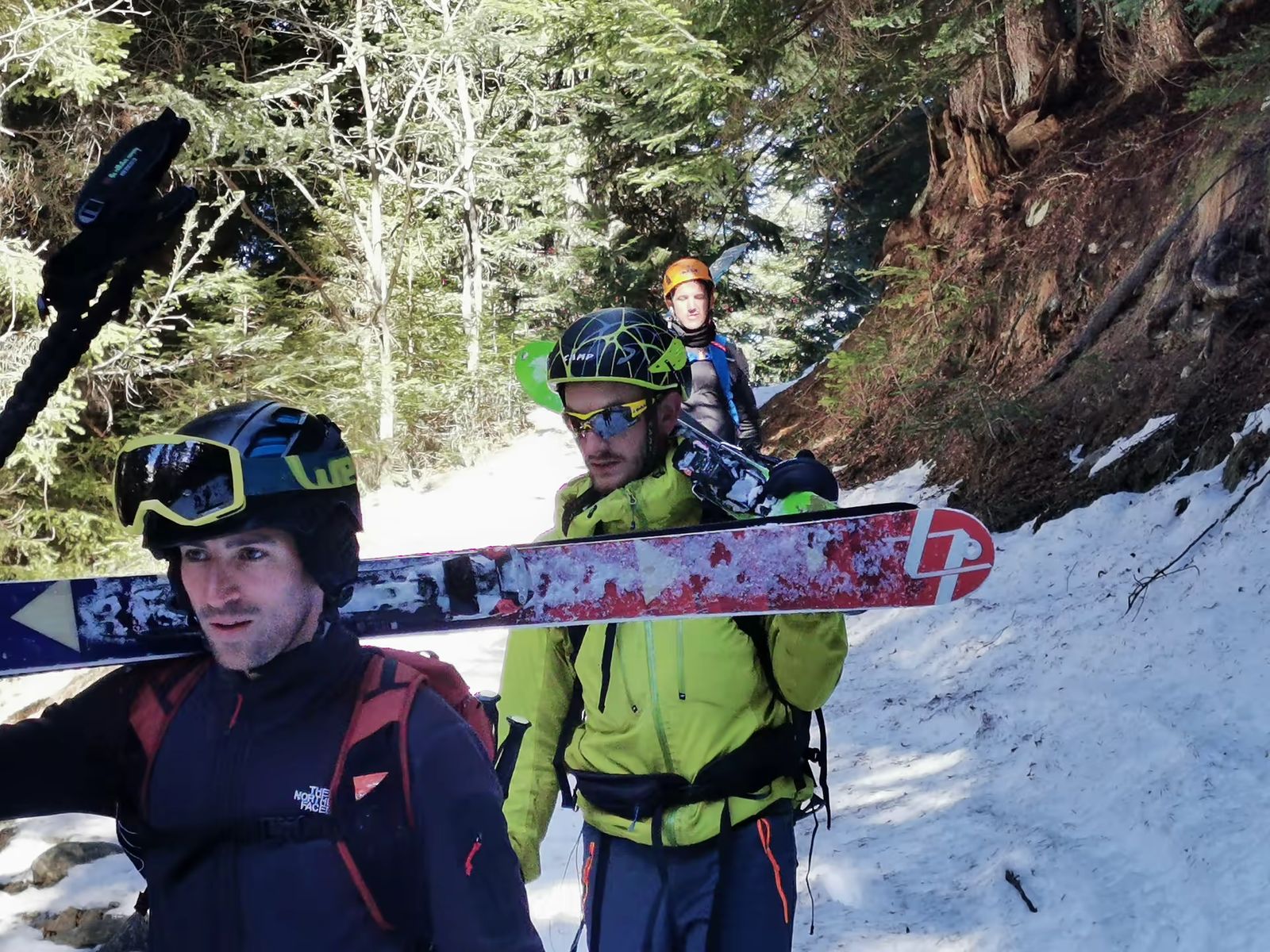 Skieurs portant leurs skis sur un sentier forestier du Mercantour