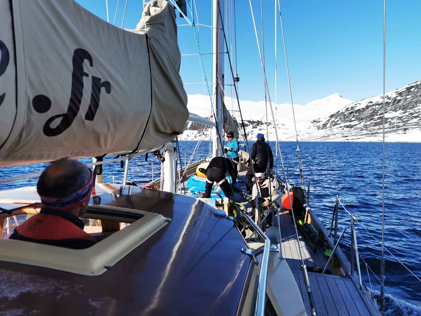 Navigation à bord du voilier La Louise entre les montagnes enneigées des fjords du Groenland