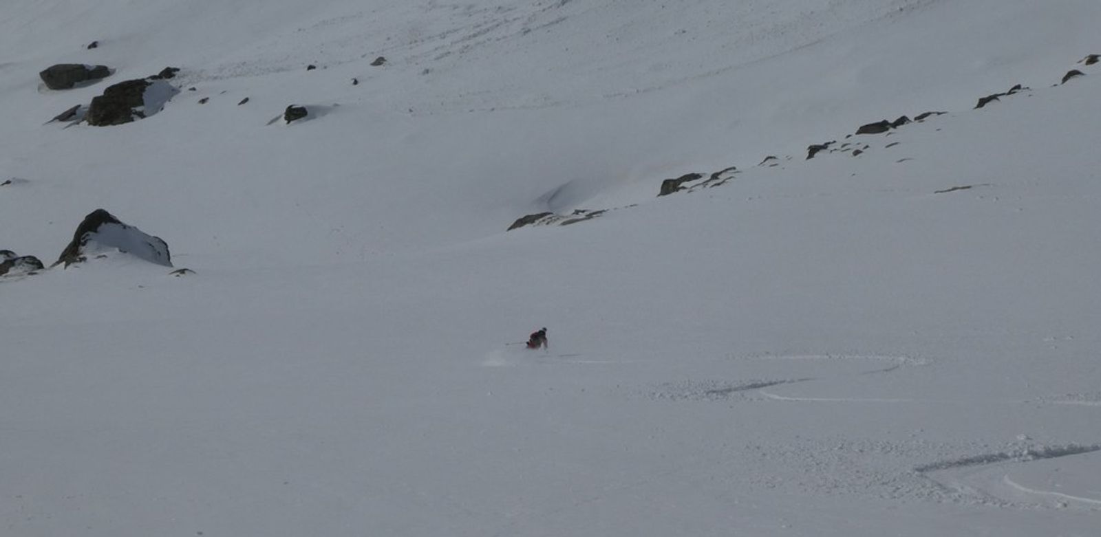 Skieur soulevant un nuage de poudreuse dans la descente vers l’Orgère.