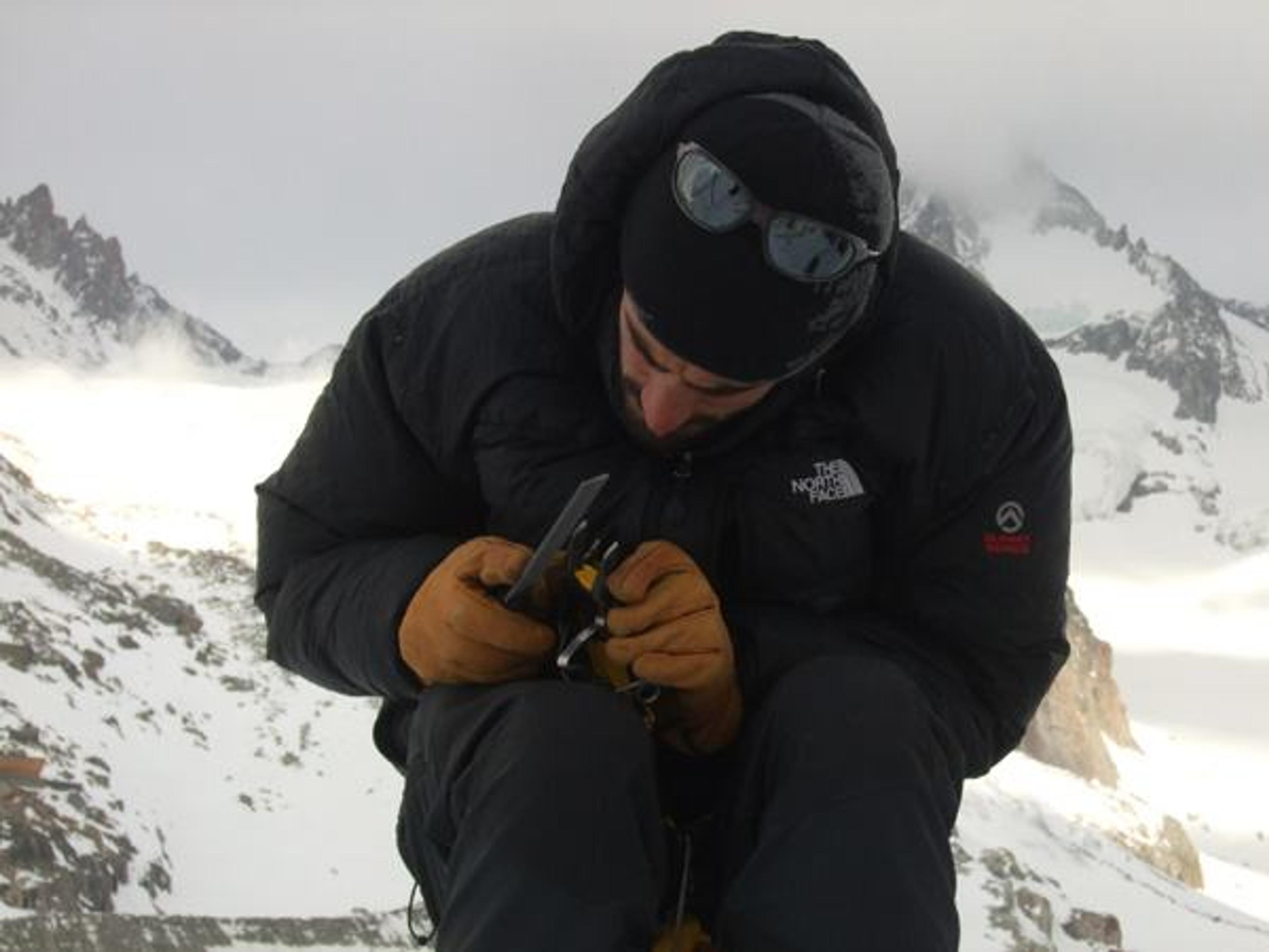Nico affute ses crampons au pied des Droites
