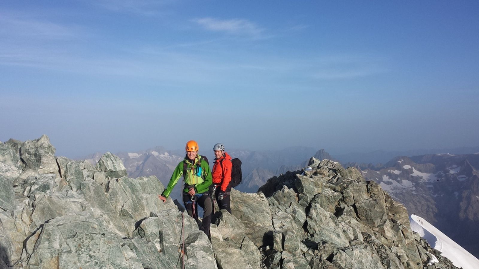 Nico et Caro progressent sur l’arête rocheuse de la Barre des Écrins sous un ciel bleu.