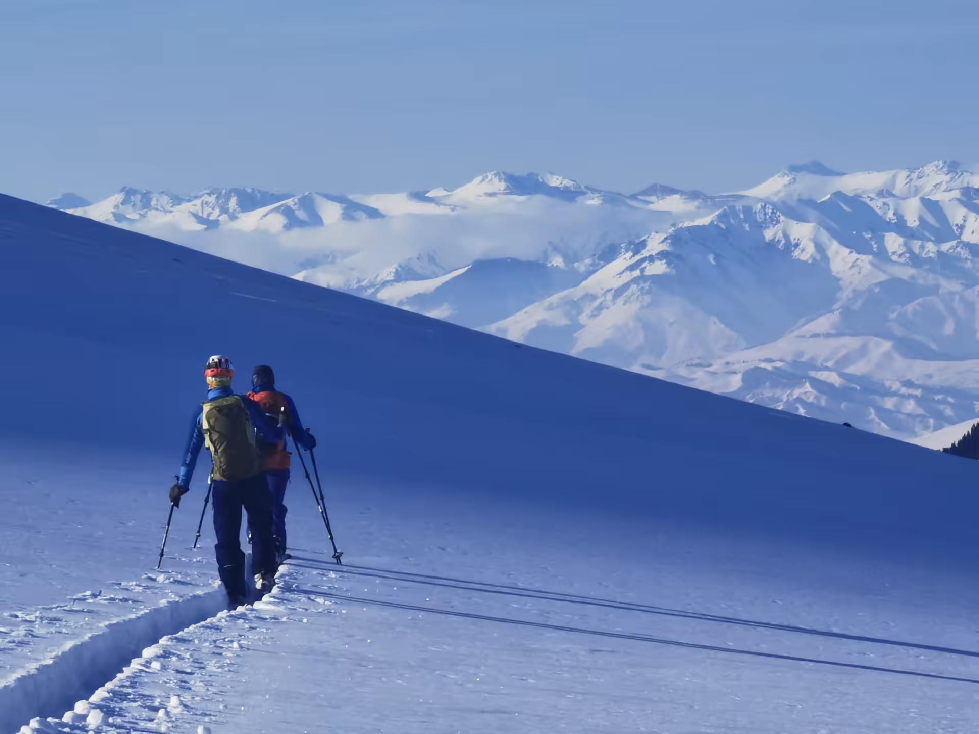 Skieurs en train de tracer devant un paysage sompeux et une lumière féérique
