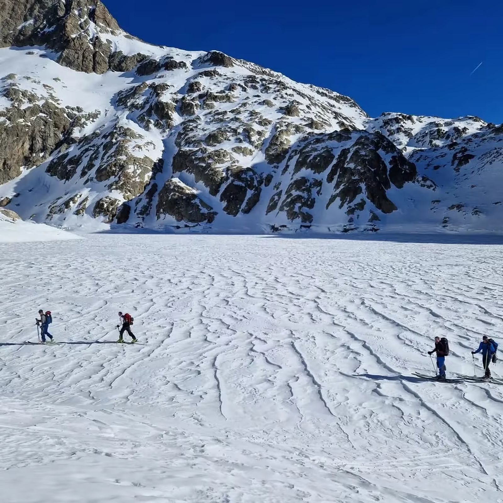 Groupe de skieurs traversant un lac enneigé dans le Mercantour